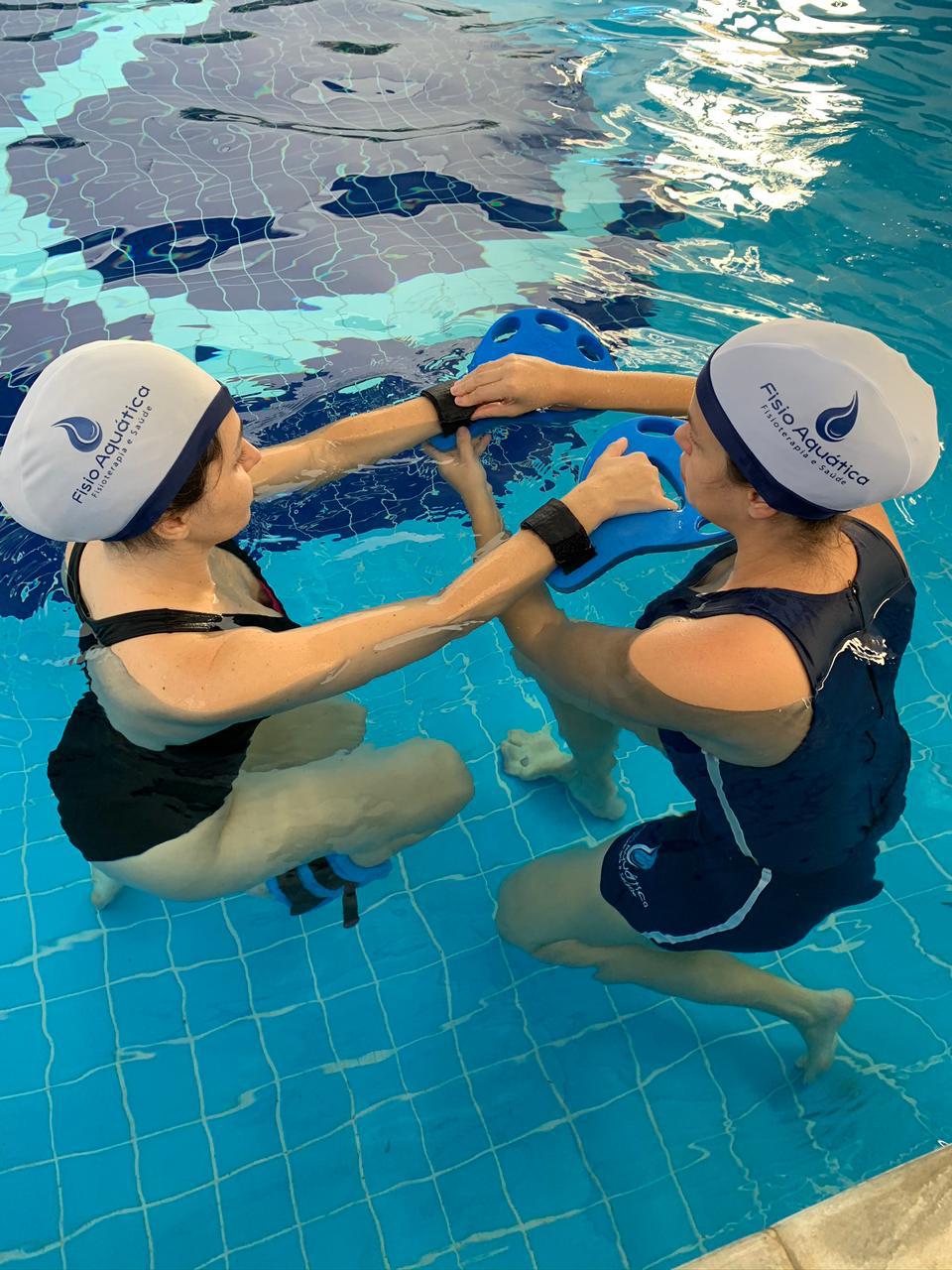 Fisioterapeuta conduzindo exercício aquático com paciente na piscina da Fisio Aquática